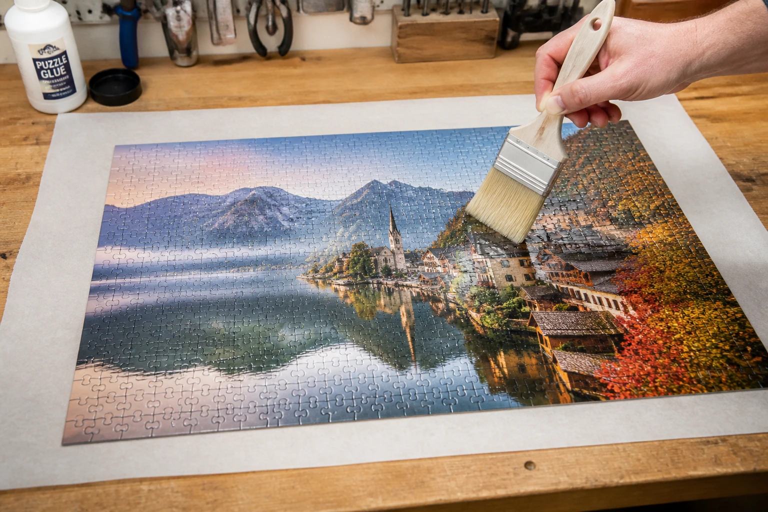 Application de colle spéciale puzzle sur un puzzle de 1000 pièces avec un pinceau plat, fond atelier bois