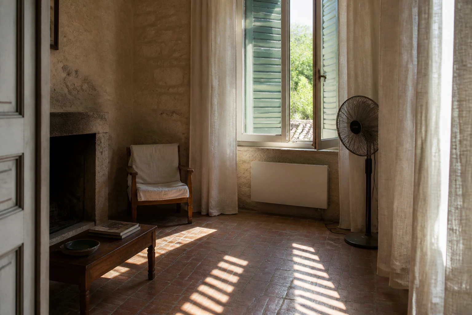 Pièce fraîche en été avec volets mi-clos, ventilateur sur pied et rideaux en lin