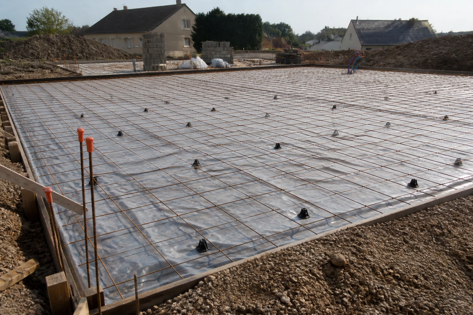Coupe de sol montrant hérisson drainant, film polyane et ferraillage avant coulage de dalle béton