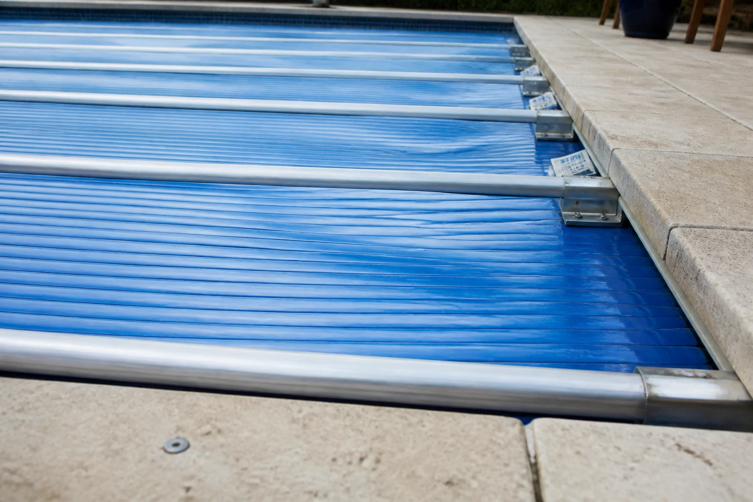 Bâche à barres rigide bleue sur piscine extérieure avec déformation visible des lamelles PVC