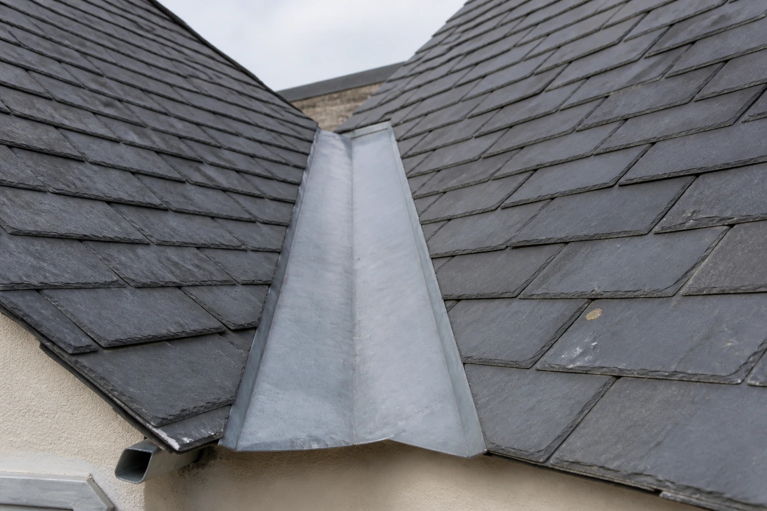 Noue toiture en zinc sur une couverture en ardoise, vue rapprochée du creux entre deux versants