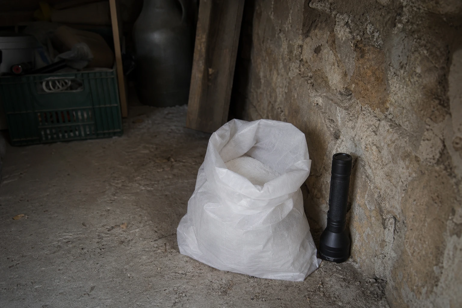 Sac de sel de cuisine posé dans une cave contre un mur en pierre, ambiance dératisation domestique
